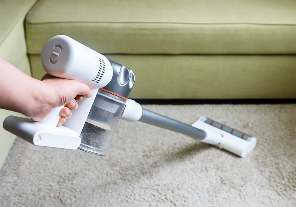 Person vacuuming a carpet | Vic's Carpet & Flooring